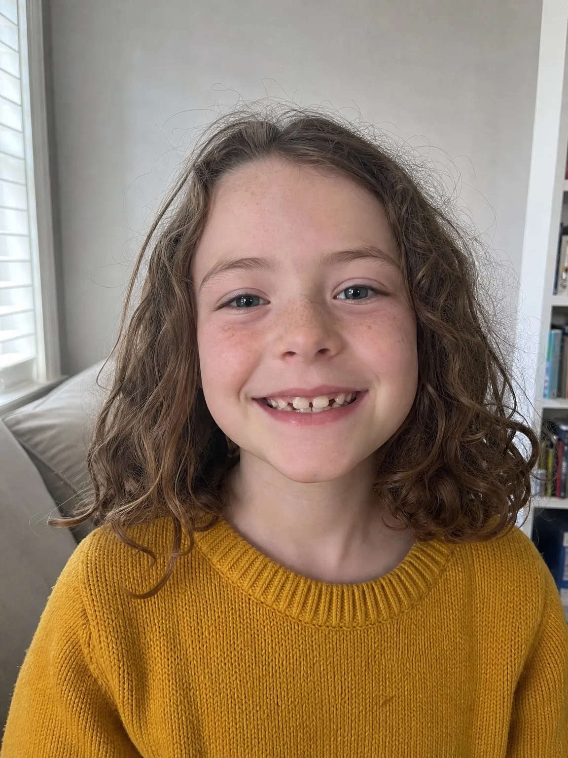 Foto di esempio di una bambina sorridente con i capelli castani ricci. Generata con l’IA, non è una bambina reale.