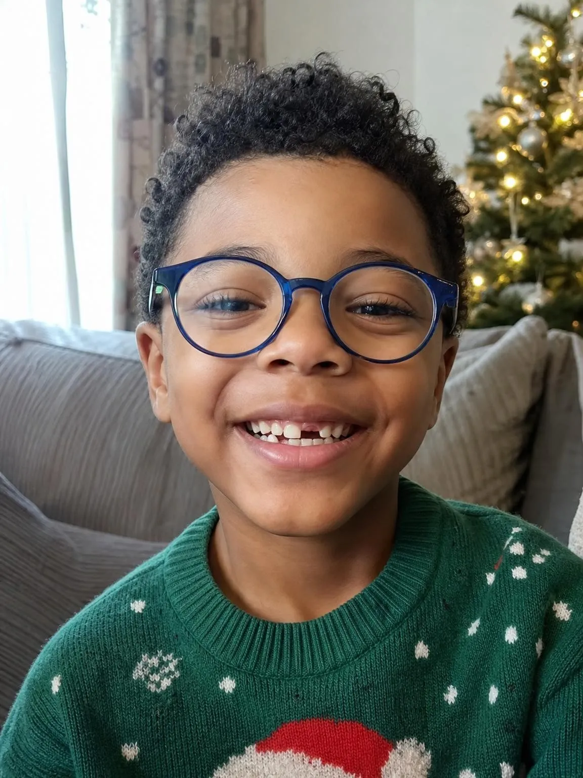 Beispielfoto: ein Junge mit schwarzen Locken, blauer Brille und einer Zahnlücke vorne. Mit KI erzeugt, kein echtes Kind.
